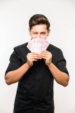 Beyaz arka planda tek başına dururken elinde banknot tutan yakışıklı Hintli adam.