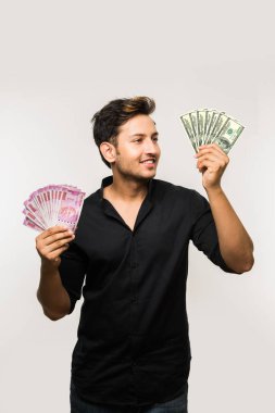 Beyaz arka planda tek başına dururken elinde banknot tutan yakışıklı Hintli adam.