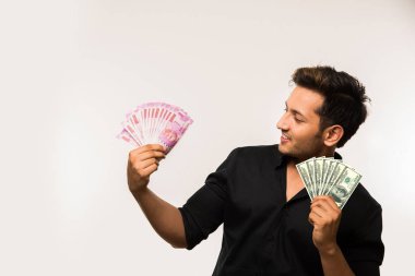 Beyaz arka planda tek başına dururken elinde banknot tutan yakışıklı Hintli adam.