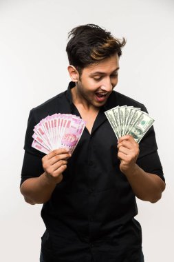 Beyaz arka planda tek başına dururken elinde banknot tutan yakışıklı Hintli adam.