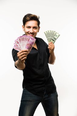 Beyaz arka planda tek başına dururken elinde banknot tutan yakışıklı Hintli adam.