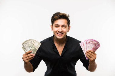 Beyaz arka planda tek başına dururken elinde banknot tutan yakışıklı Hintli adam.