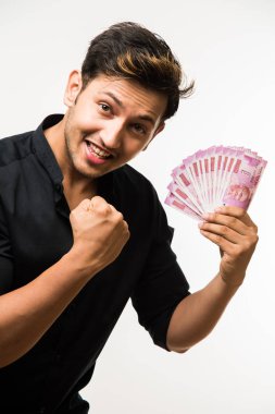 Beyaz arka planda tek başına dururken elinde banknot tutan yakışıklı Hintli adam.