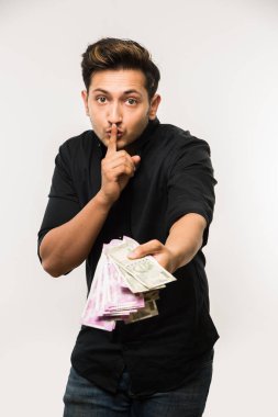 Beyaz arka planda tek başına dururken elinde banknot tutan yakışıklı Hintli adam.