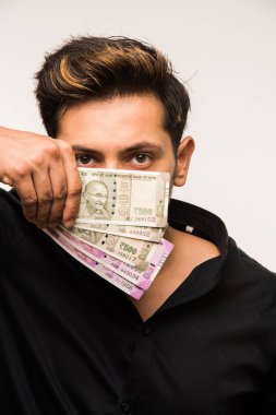 Beyaz arka planda tek başına dururken elinde banknot tutan yakışıklı Hintli adam.