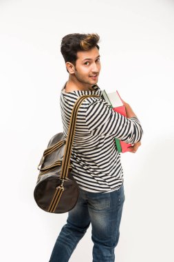 Yakışıklı Hintli erkek üniversite öğrencisi kitap ve çantayla duruyor, beyaz arka plana karşı, izole