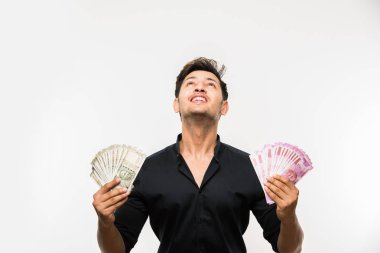 Yakışıklı Hintli adam elinde kağıt para banknotları tutuyordu. 500 ya da 2000 rupi, beyaz arka planda tek başına duruyordu.