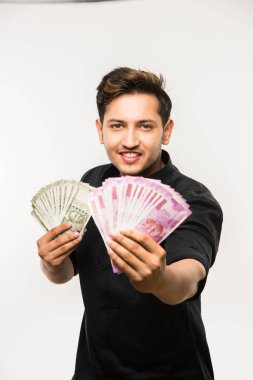 Yakışıklı Hintli adam elinde kağıt para banknotları tutuyordu. 500 ya da 2000 rupi, beyaz arka planda tek başına duruyordu.