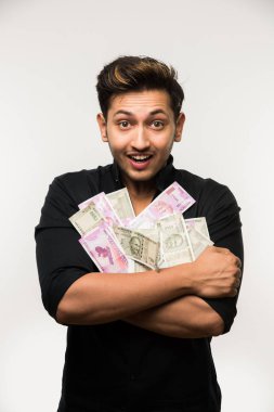 Yakışıklı Hintli adam elinde kağıt para banknotları tutuyordu. 500 ya da 2000 rupi, beyaz arka planda tek başına duruyordu.
