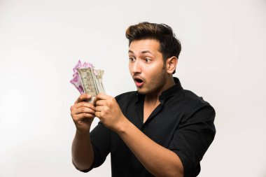 Yakışıklı Hintli adam elinde kağıt para banknotları tutuyordu. 500 ya da 2000 rupi, beyaz arka planda tek başına duruyordu.