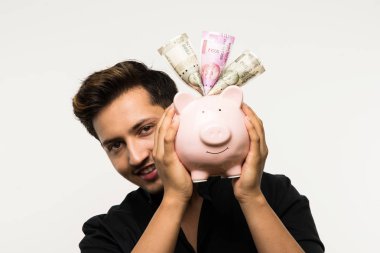 Kumbaralı Hintli yakışıklı genç adam ya da farklı ifadeli para kutusu, beyaz arka planda tek başına duruyor.