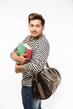 Yakışıklı ve genç Hintli erkek üniversite öğrencisi kolej kitaplar, dizüstü bilgisayar ya da akıllı telefon tutarak beyaz arka plan üzerinde çanta