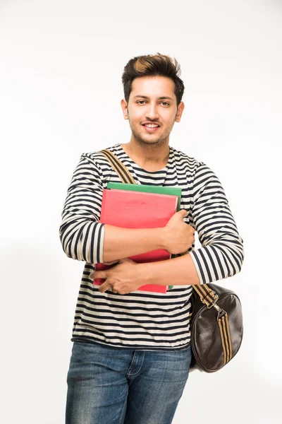 Yakışıklı ve genç Hintli erkek üniversite öğrencisi kolej kitaplar, dizüstü bilgisayar ya da akıllı telefon tutarak beyaz arka plan üzerinde çanta