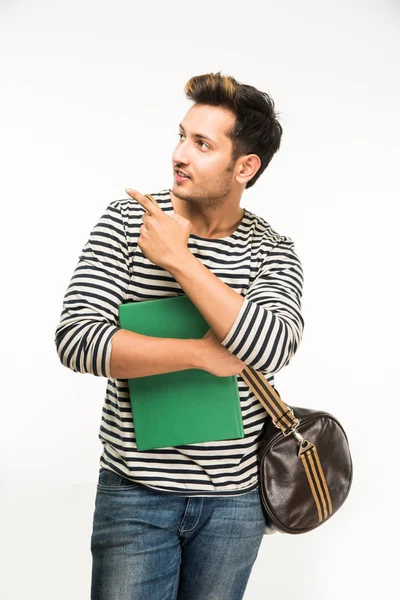Knappe en jonge Indiase mannelijke college student draagtas op witte achtergrond terwijl college boeken, laptop of slimme telefoon — Stockfoto
