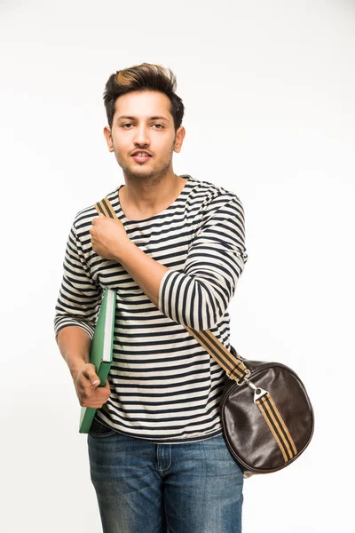 Stilig och unga indiska manliga collegestudent väska på vit bakgrund medan du håller college böcker, bärbar dator eller smart telefon — Stockfoto