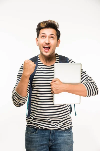 Młody i przystojny mężczyzna Indyjski college student torba na białym tle trzymając książek kolegium, laptopa lub smartfona — Zdjęcie stockowe