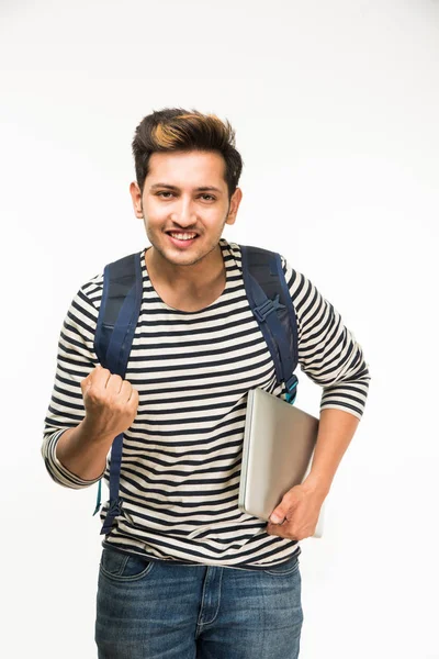 Beau et jeune étudiant indien mâle portant sac sur fond blanc tout en tenant des livres d'université, ordinateur portable ou téléphone intelligent — Photo