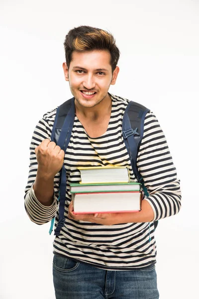 Beau et jeune étudiant indien mâle portant sac sur fond blanc tout en tenant des livres d'université, ordinateur portable ou téléphone intelligent — Photo
