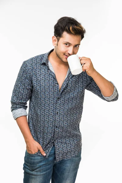 Bir fincan kahve, beyaz arka plan üzerinde izole ayakta olan genç yakışıklı bir Hintli adam portresi