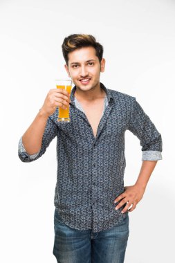 Genç Hintli adam bira içiyor ve beyaz arka planda kameraya bakıyor.