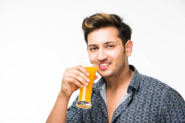 Genç yakışıklı Hintli adam rahat gömlek içme veya bir bardak taze portakal suyu veya kahvaltı için gazlı içecek dolu. 