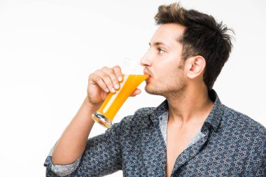 Genç yakışıklı Hintli adam rahat gömlek içme veya bir bardak taze portakal suyu veya kahvaltı için gazlı içecek dolu. 