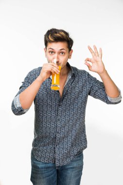 Genç yakışıklı Hintli adam rahat gömlek içme veya bir bardak taze portakal suyu veya kahvaltı için gazlı içecek dolu. 