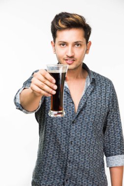 Genç yakışıklı Hintli adam rahat gömlek içme veya bir bardak taze portakal suyu veya kahvaltı için gazlı içecek dolu. 