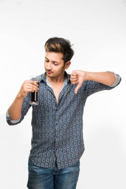 Genç yakışıklı Hintli adam rahat gömlek içme veya bir bardak taze portakal suyu veya kahvaltı için gazlı içecek dolu. 