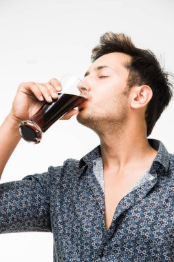 Genç yakışıklı Hintli adam rahat gömlek içme veya bir bardak taze portakal suyu veya kahvaltı için gazlı içecek dolu. 