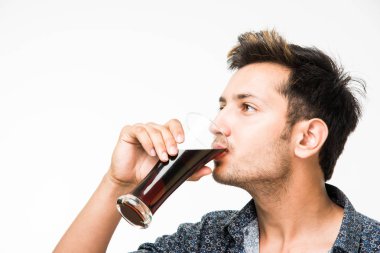 Genç yakışıklı Hintli adam rahat gömlek içme veya bir bardak taze portakal suyu veya kahvaltı için gazlı içecek dolu. 