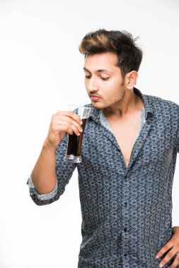 Genç yakışıklı Hintli adam rahat gömlek içme veya bir bardak taze portakal suyu veya kahvaltı için gazlı içecek dolu. 