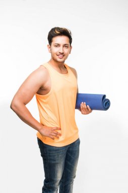 Hintli genç yakışıklı adam holding yoga ya da egzersiz minderi ve cam sonrası egzersiz veya yoga taze meyve suyu bir yudum sahip / asana, izole beyaz arka plan üzerinde