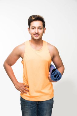 Hintli genç yakışıklı adam holding yoga ya da egzersiz minderi ve cam sonrası egzersiz veya yoga taze meyve suyu bir yudum sahip / asana, izole beyaz arka plan üzerinde