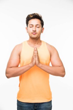 Yakışıklı Hintli adam ya da iki eliyle bir arada Namaskara içinde tutan çocuk / namaskaram / pranamımı poz veya mudra trendy görünümlü turuncu sleev tişört, beyaz arka plan üzerinde ayakta daha az giyen süre