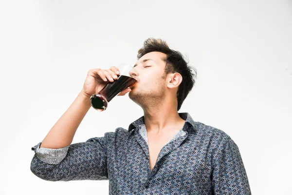 Homem indiano bonito novo na bebida casual da camisa ou em um copo cheio do suco de laranja fresco ou da bebida aerated para o café da manhã . — Fotografia de Stock