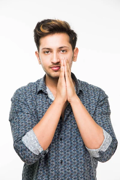 Porträtt av bra söker indiska eller asiatiska ung man i casual dressing med knäppta händer mot bakgrund — Stockfoto