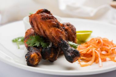 Tavuk Tangri kabab veya kebap - sonra ızgara ve salata ile servis kırmızı sos ile marine edilmiş üç tavuk bacak parçaları. Bu yeşil Hint turşusu ile servis edilebilir