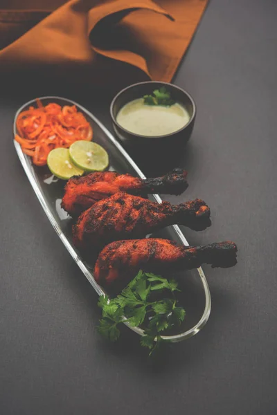 Pollo Tangri kabab o kebab - tres trozos de pata de pollo marinado con salsa roja a la parrilla y servido con ensalada. Se puede servir con chutney verde —  Fotos de Stock
