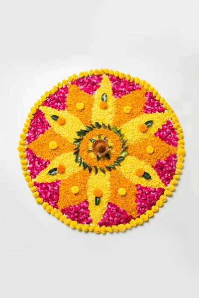 Rangoli Diwali için çiçek veya pongal diwali diya orta, seçici odak ile beyaz arka plan üzerinde kadife çiçeği veya zendu çiçekler ve kırmızı gül yaprakları kullanılarak yapılan