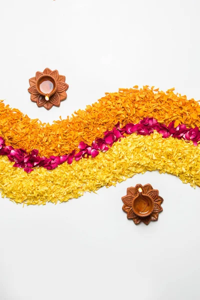 Blume-Rangoli für Diwali oder Pongal aus Ringelblumen- oder Zendu-Blüten und roten Rosenblättern auf weißem Hintergrund mit Diwali-Diya in der Mitte, selektiver Fokus — Stockfoto