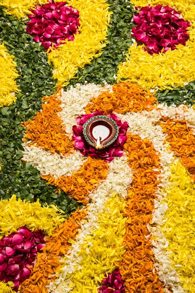 Flower rangoli for Diwali or pongal or onam made using marigold or zendu flowers and red rose petals over white background with diwali diya in the middle, selective focus — Stock Photo, Image