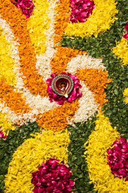 çiçek rangoli Diwali için veya pongal veya diwali diya orta, seçici odak ile beyaz arka plan üzerinde kadife çiçeği veya zendu çiçekler ve kırmızı gül yaprakları kullanılarak yapılan onam