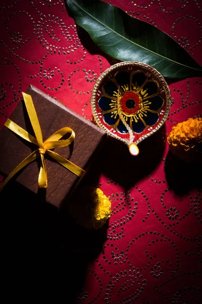 Archivfoto der schönen Diwali Diya mit Geschenken und Blumen, über dekorativem Hintergrund, stimmungsvoller Beleuchtung und selektivem Fokus — Stockfoto