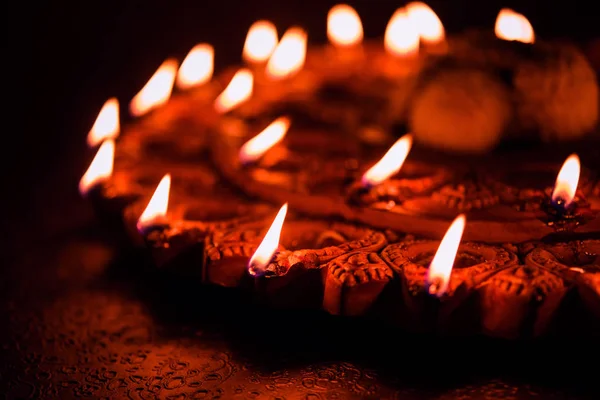 Oświetlony terra-cotta Diwali Lampa lub Diya z szczegółowe grafiki na to zdjęcie. na tle nastrojowa i Selektywny fokus — Zdjęcie stockowe
