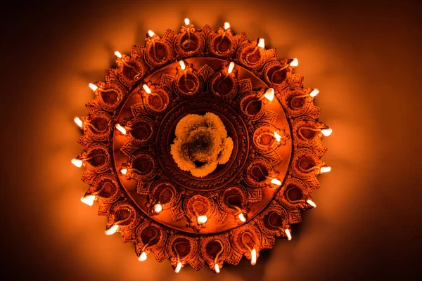 Foto de una lámpara Diwali de terracota iluminada o Diya con obras de arte detalladas. sobre un fondo malhumorado y enfoque selectivo —  Fotos de Stock