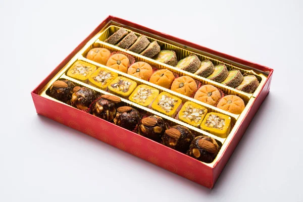 Photo de stock de bonbons indiens servis dans une assiette en argent ou en bois. variété de Peda, burfi, laddu en plaque décorative, mise au point sélective — Photo