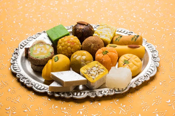 Foto di scorta di dolci indiani serviti in argento o piatto di legno. varietà di Peda, burfi, laddu in lastra decorativa, messa a fuoco selettiva — Foto Stock