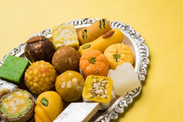 Φωτογραφία απόθεμα ινδική γλυκά σερβίρεται στην ασημένια ή ξύλινα πλάκα. ποικίλες Peda, burfi, laddu σε διακοσμητικό πιάτο, επιλεκτική εστίαση — Φωτογραφία Αρχείου