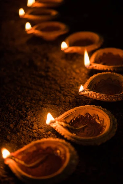 Happy Diwali - muchas lámparas de terracota diya o aceite dispuestas sobre la superficie de arcilla o el suelo en una línea o forma curva o zigzag, enfoque selectivo —  Fotos de Stock